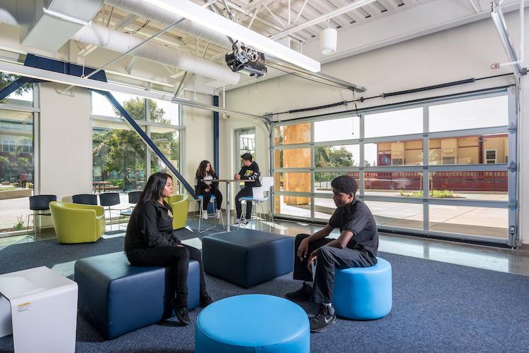 The Foundation for Hispanic Education (TFHE) students chatting in sun-filled atrium on comfortable seating