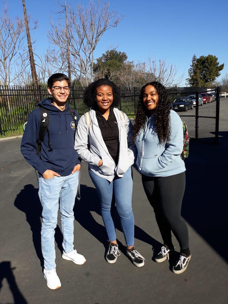 Luis Valdez Leadership Academy (LVLA) and three students standing together on campus in the sun